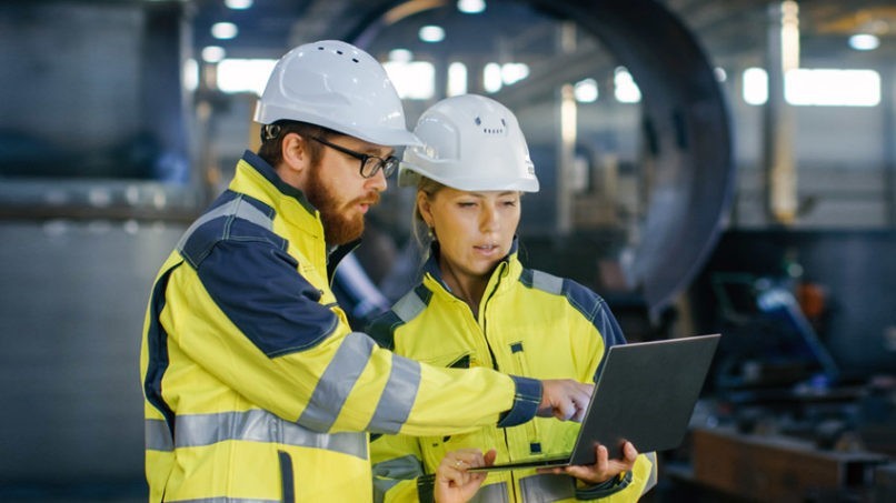 General contractors and electricians looking at a computer inspecting drawings.