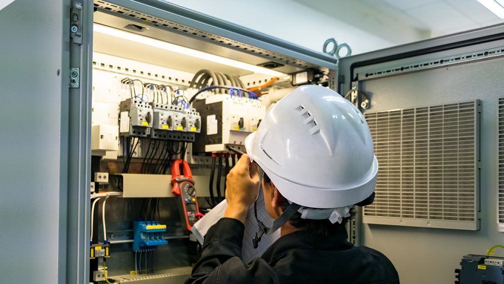 Electrician inspecting the electrical service of a commercial building.