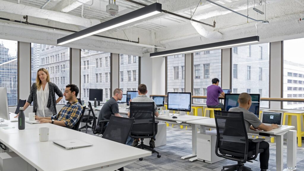 An office with track lights hanging from the ceiling.