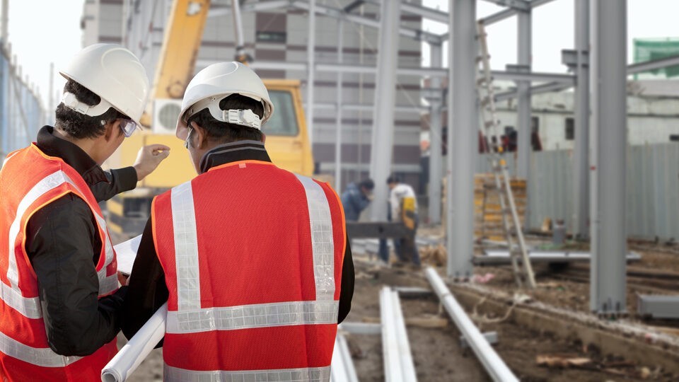 A commercial electrician and general contractor looking at blueprints for a commercial job site.