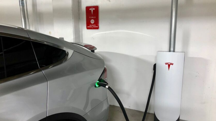 A tesla car in a residential building garage being charged.