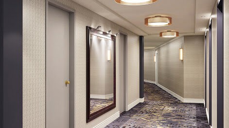 Corridor of a residential building with ceiling lights and in wall lighting installations.