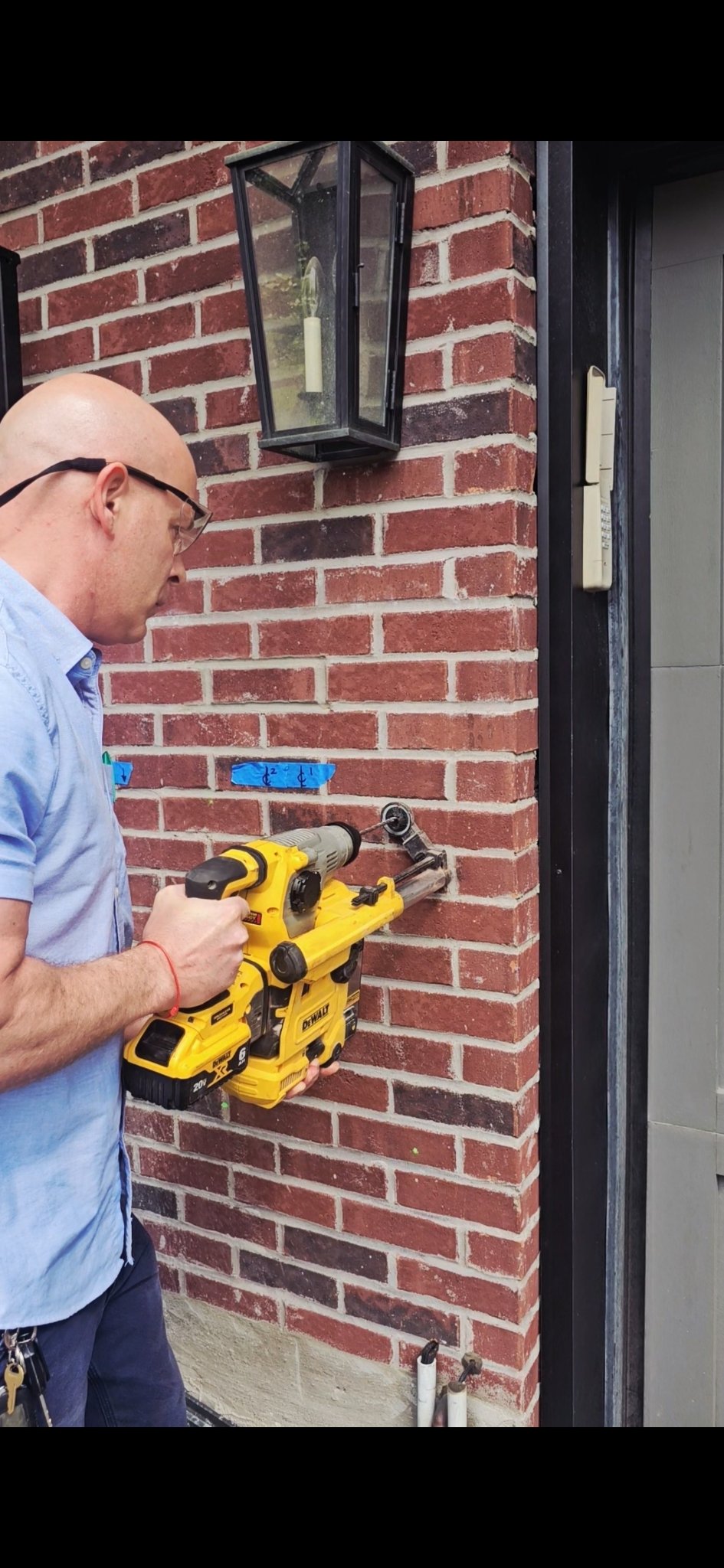 3E electrician drilling to mount an EV charger beside a Ford Charge Station Pro in a Toronto garage