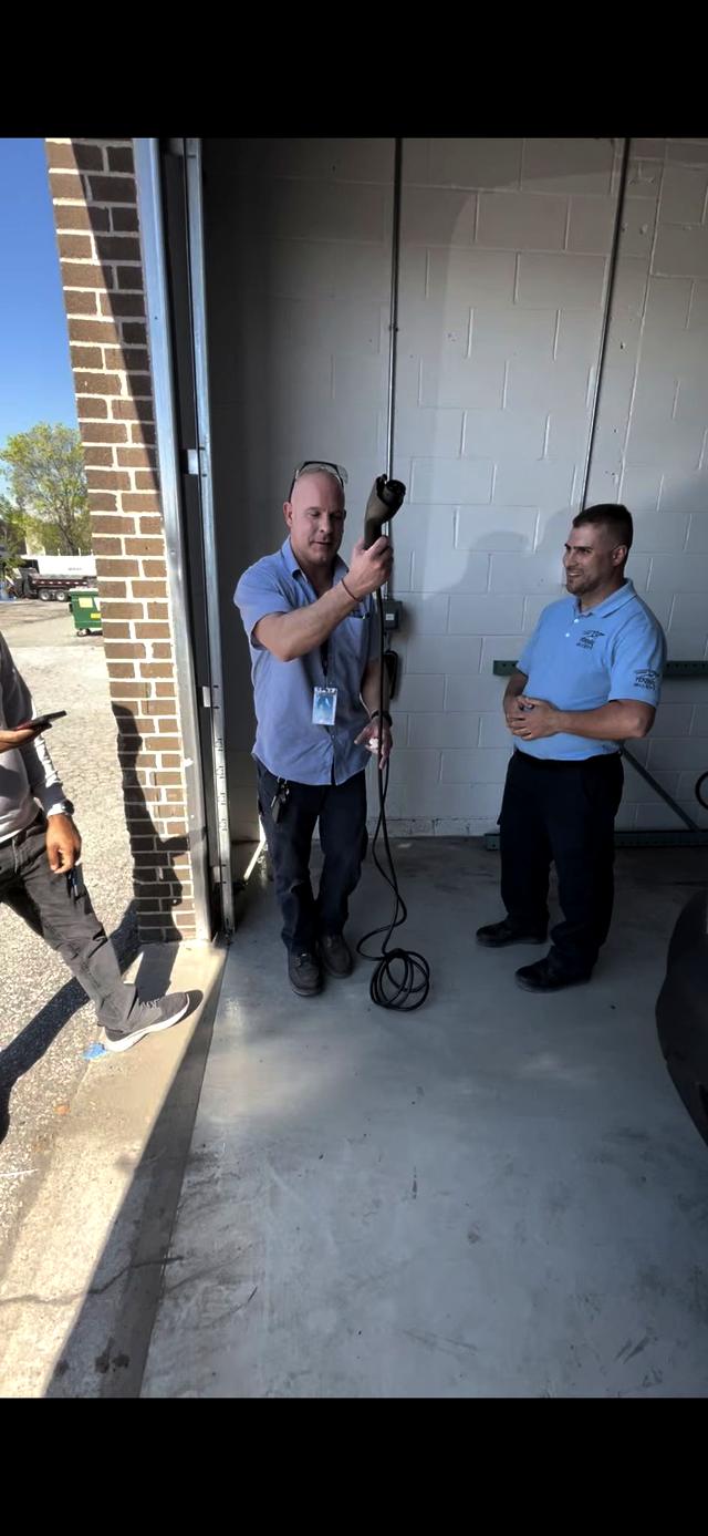 Two 3E electricians holding an EV charging connector at a finished home install in the GTA