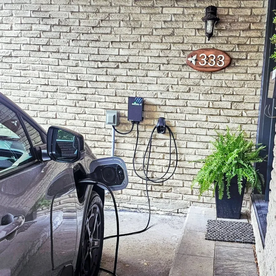 EV charger installation by 3e Electrical — Grizzl-E charger on a brick wall with an SUV plugged in