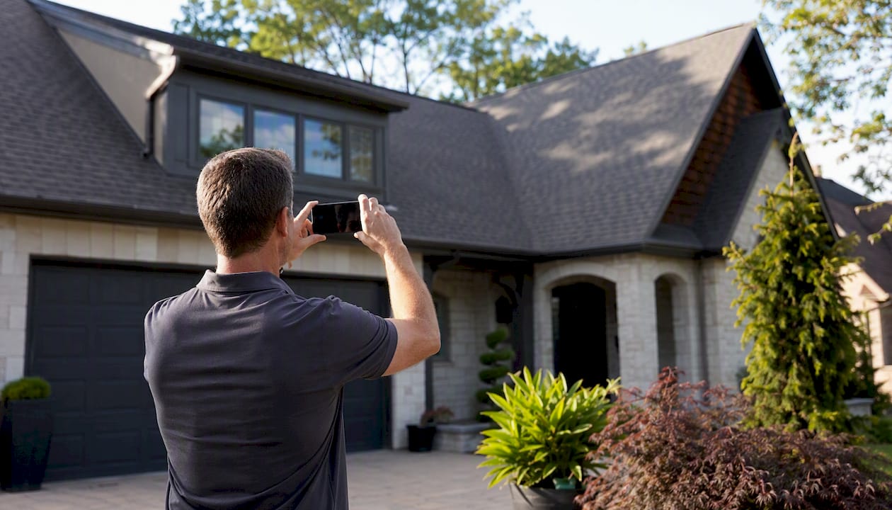 A homeowner photographing the outside of his house with his phone